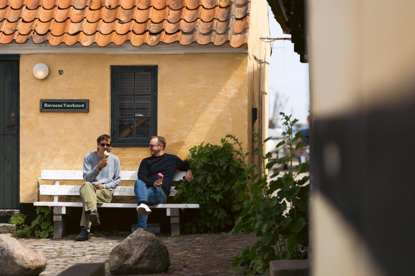 To mænd spiser is på en bænk i Dragør Gamle By